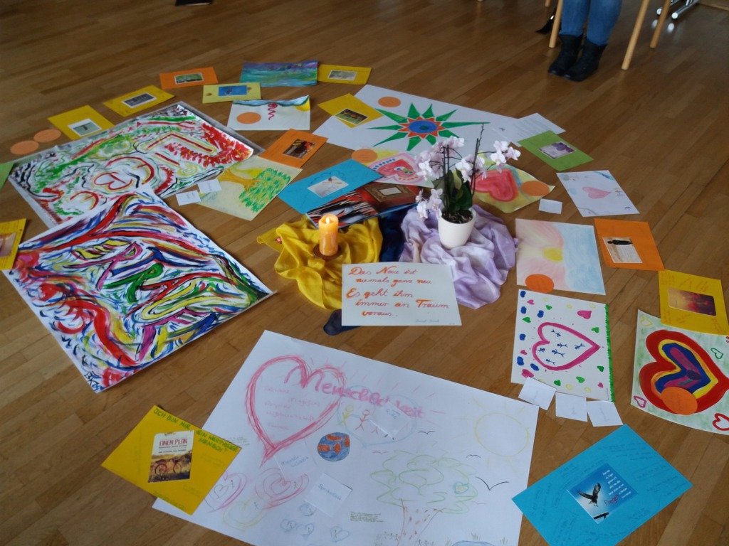 Bunte Herzbilder, Kerze und Orchidee bilden eine Mitte auf dem Holzboden des Seminarraums
