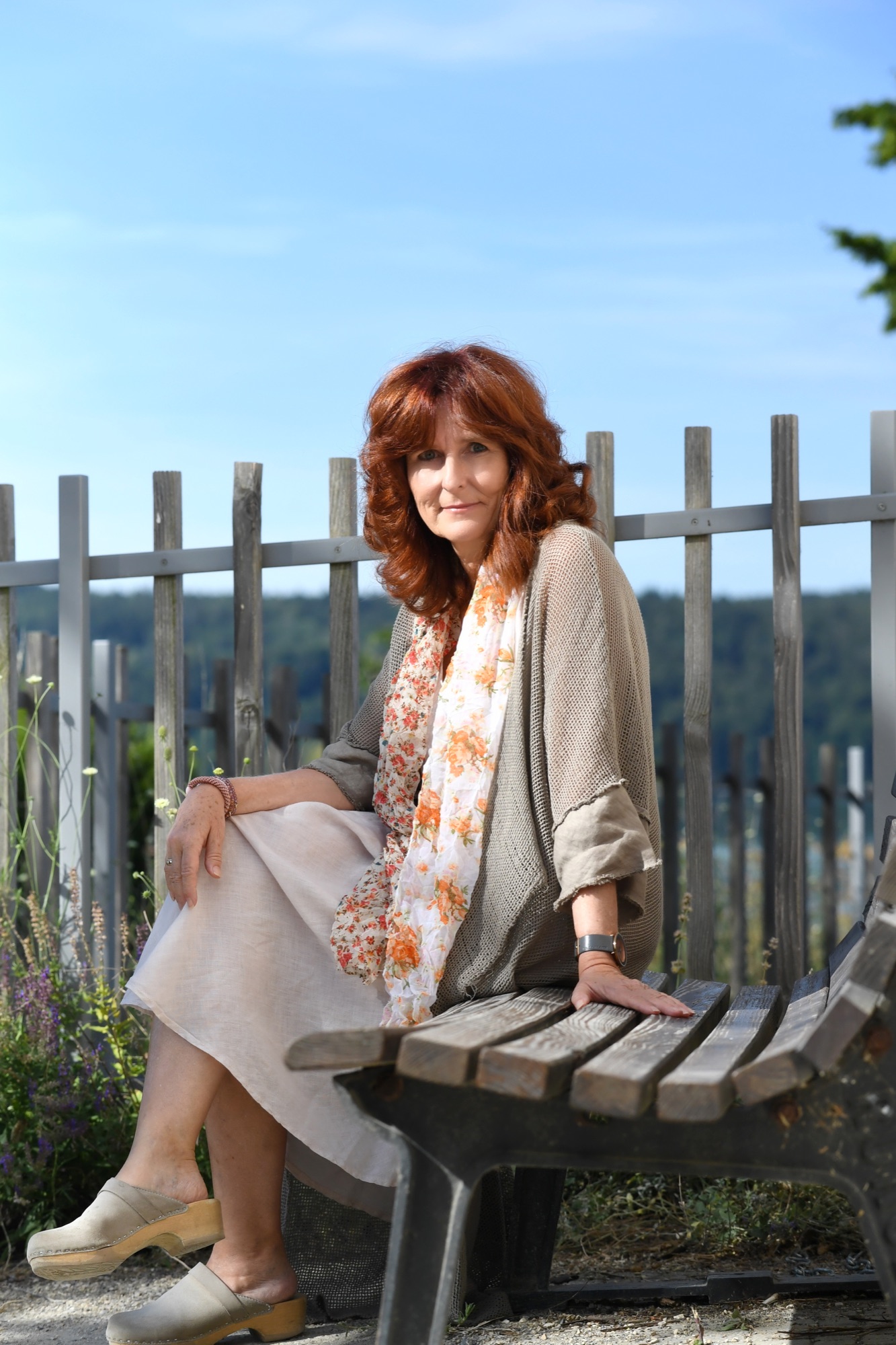 Sabine Jahn sitzt auf einer Holzbank mit Blick auf den Bodensee